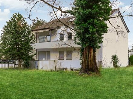 Ein großes Mehrfamilienhaus mit angrenzendem Baugrundstück und einem ausgedehnten Gartenbereich.