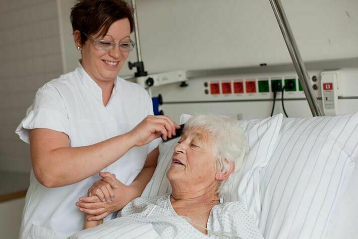 Eine Pflegekraft frisiert eine Patientin.