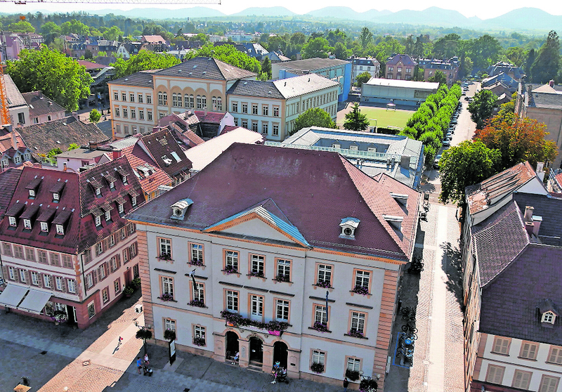 Das Landauer Rathaus, im Hintergrund ein Teil des Rebenmeeres an der Südlichen Weinstraße und Hügel des Pfälzerwaldes. Foto: srä