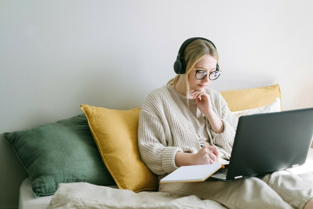 Eine Frau sitzt mit Kopfhörern vor ihrem Laptop