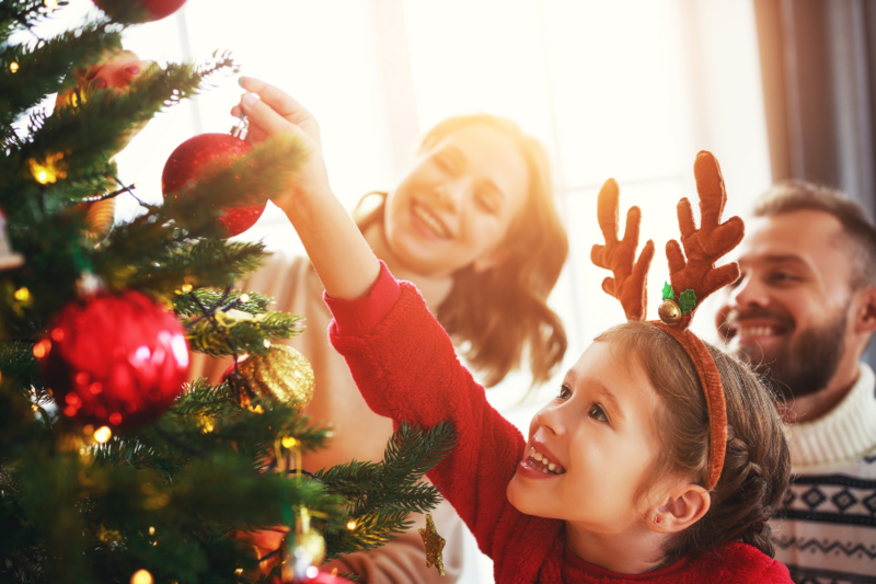 Eine Familie schmückt den Weihnachtsbaum. 