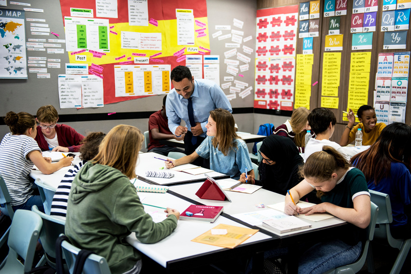 Lehrer unterstützt Schüler im Klassenzimmer bei der Einzelarbeit