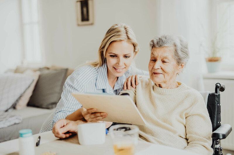 Pflegerin hilft Seniorin Patientendokumente zu lesen.
