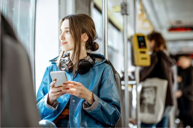 Ein Mädchen sitzt in der Bahn und hat ein Handy in der Hand