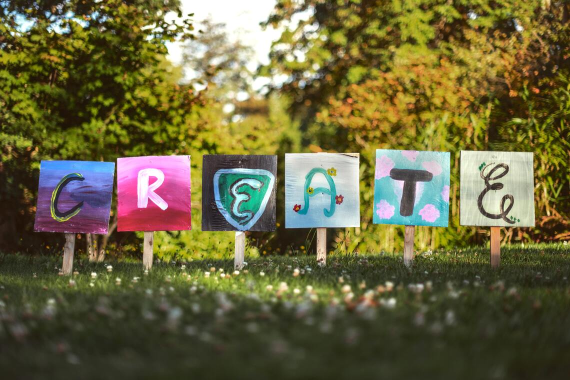 Das Wort Creativ als bunte Schilder in einem Garten