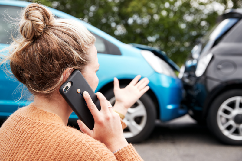 Frau steht vor einem Unfallwagen