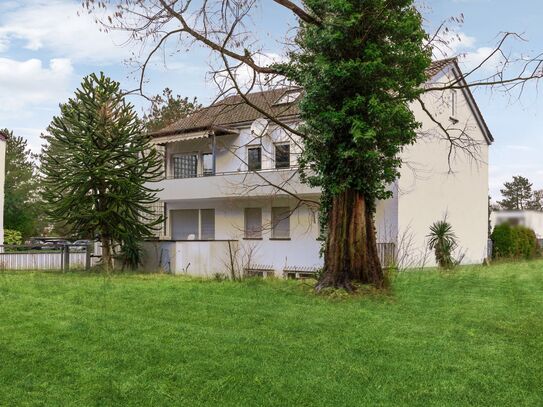 Ein großes Mehrfamilienhaus mit angrenzendem Baugrundstück und einem ausgedehnten Gartenbereich.